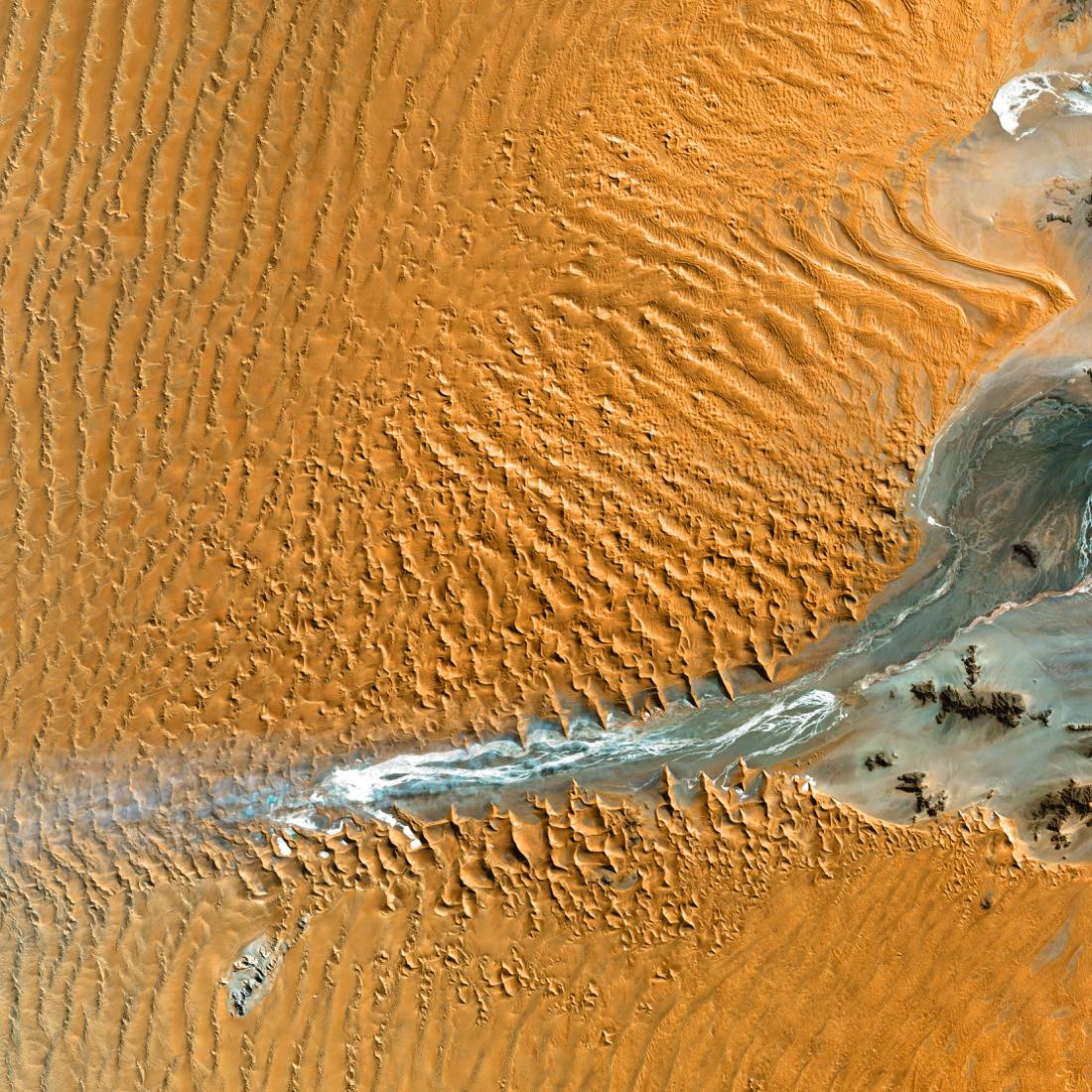 Rust red dune ridges and a pale dry channel in Namibia, Landsat false color
